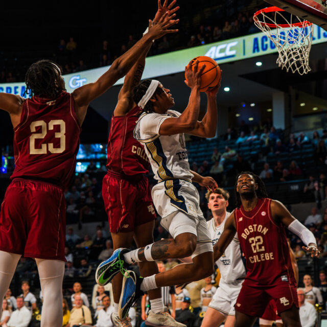 Guard Akai Fleming #0 splits two defenders on his way to the basket.