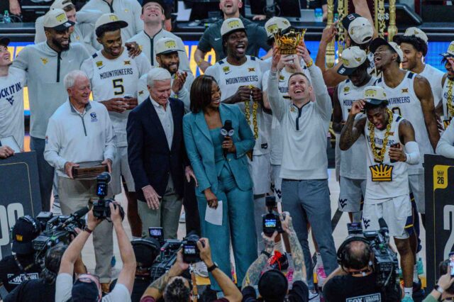 West Virginia Head Coach Ross Hodge holding up the 2026 College Basketball Crown championship trophy